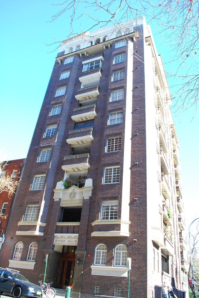 A tall brick 1930s mansion block with white balconies above a London street
